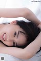 A woman laying on top of a bed with her hands behind her head.