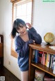 A woman standing next to a book shelf with a globe on it.