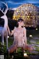 A woman kneeling down next to a white deer statue.