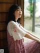 A woman sitting on a window sill looking out the window.