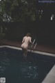 A naked woman standing in a swimming pool.