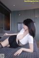 A woman in a white shirt and black skirt laying on a bed.