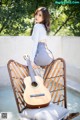 A woman sitting on a chair with a guitar.