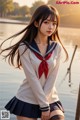 A woman in a sailor outfit posing by the water.