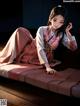 A woman in a kimono laying on a bed.