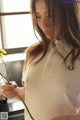 A woman in a white shirt holding a yellow flower.