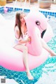 A woman sitting on an inflatable flamingo in a pool.