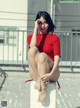 A woman in a red dress sitting on a white cube.