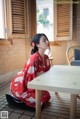 A woman in a red kimono sitting at a table.