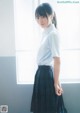 A young woman in a school uniform standing by a window.