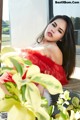 A woman in a red dress sitting on a wooden bench.