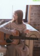 A woman sitting on a couch playing a guitar.