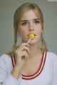 A woman holding a yellow lollipop in her mouth.