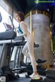 A woman is standing on a treadmills in a gym.